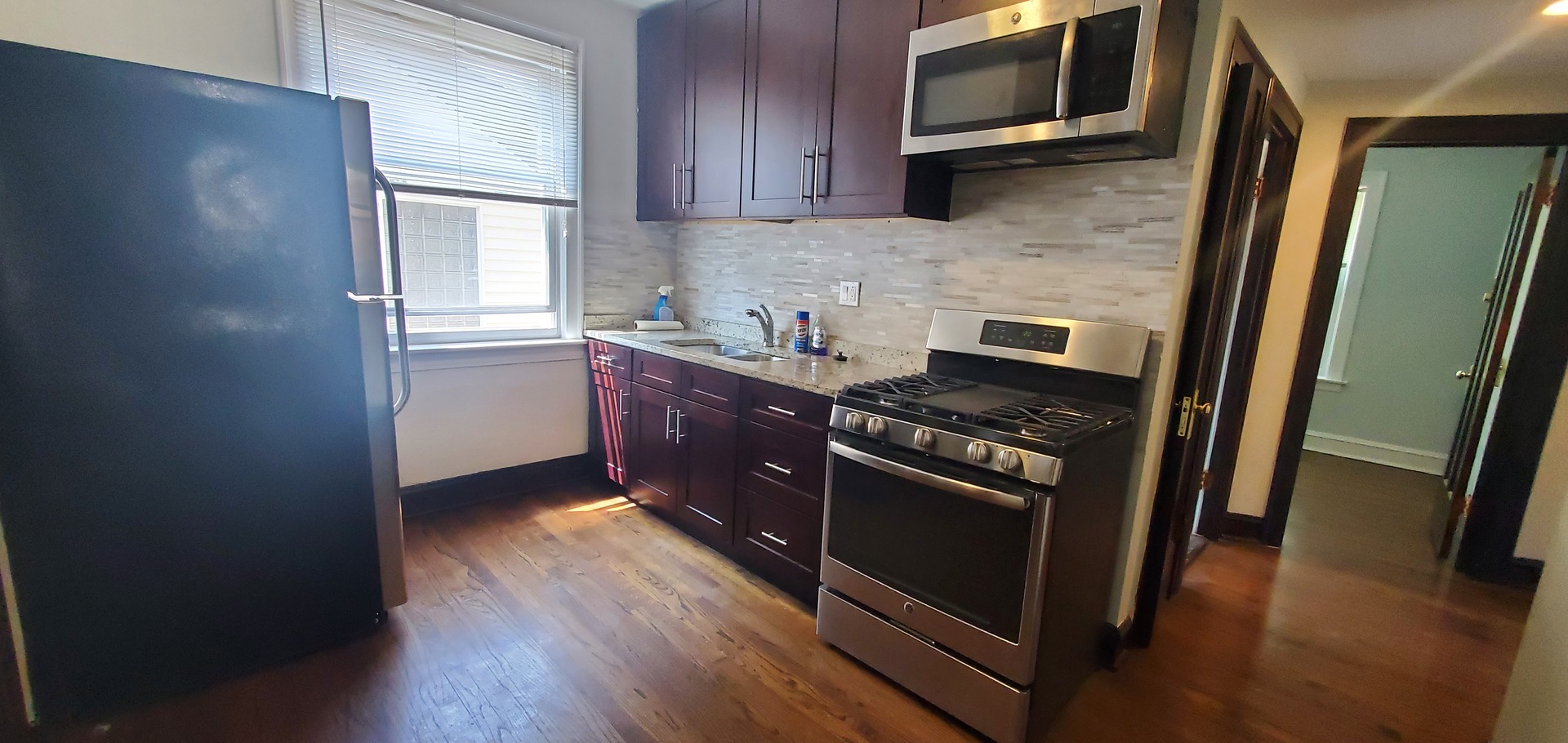 3756 North Kilpatrick Avenue, Unit 2 Chicago, IL 60641 - Photo 2 of 6 a kitchen with stainless steel appliances granite countertop a stove a microwave and a hard wood floors