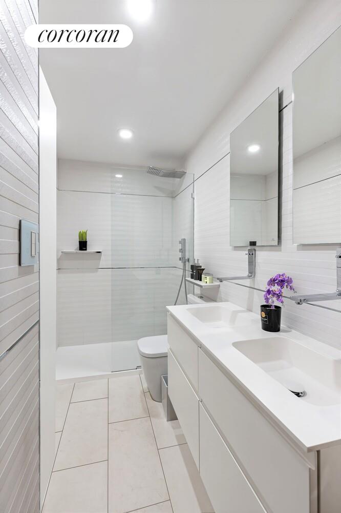1991 Broadway, Unit 21A Manhattan, NY 10023 - Photo 7 of 13 a bathroom with a sink a toilet and mirror