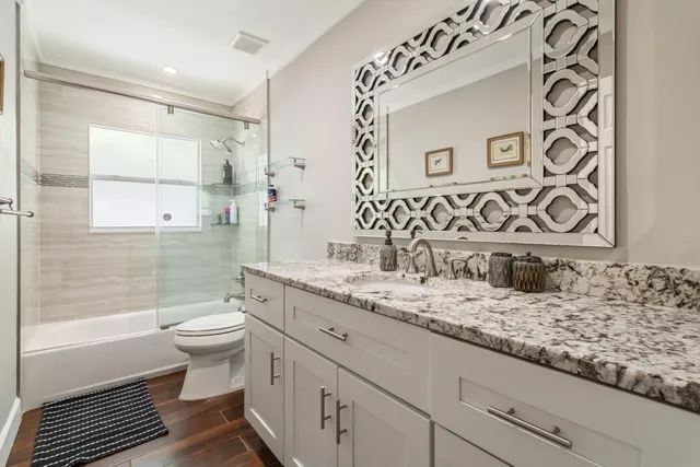 a bathroom with a granite countertop sink mirror vanity and toilet