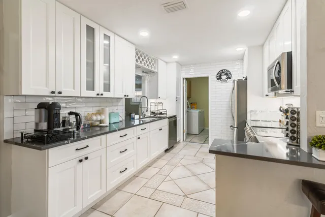 a kitchen with granite countertop white cabinets and stainless steel appliances