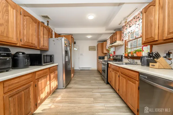 a kitchen with stainless steel appliances granite countertop a refrigerator a sink dishwasher and wooden cabinets with wooden floor