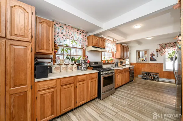 a kitchen with stainless steel appliances granite countertop a stove a sink dishwasher and a refrigerator with wooden floor