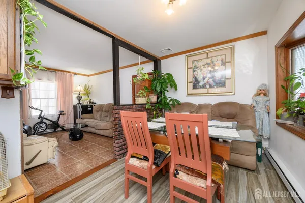 a view of a dining room with furniture one side kitchen view and wooden floor