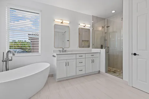 a spacious bathroom with a double vanity sink a large mirror a bathtub and shower