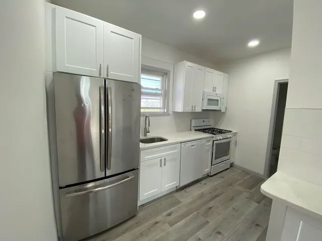 a kitchen with a refrigerator a sink and white cabinets