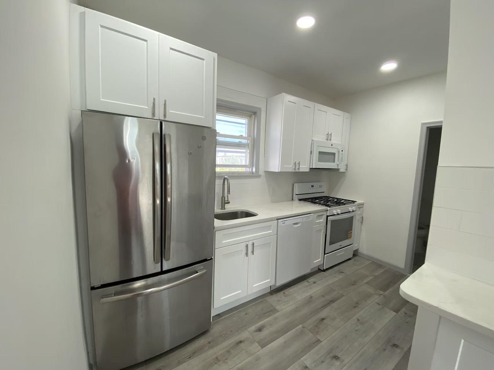 a kitchen with a refrigerator a sink and white cabinets