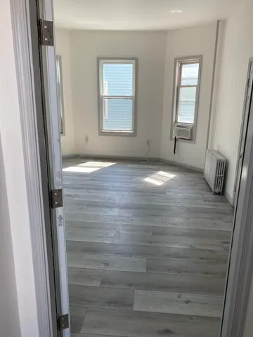 a view of empty room with window and wooden floor