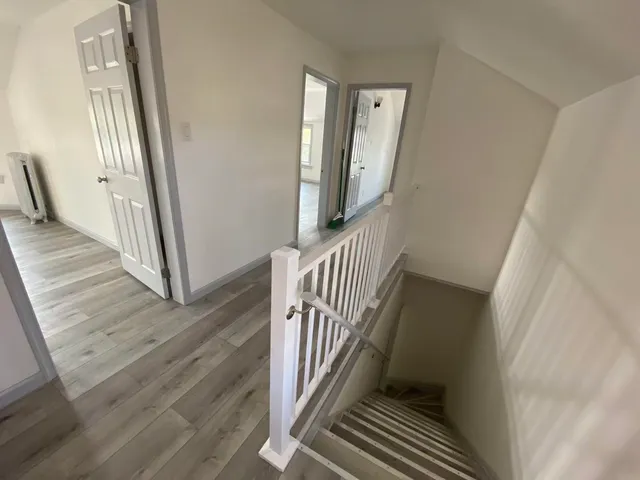 a view of a hallway with wooden floor and staircase