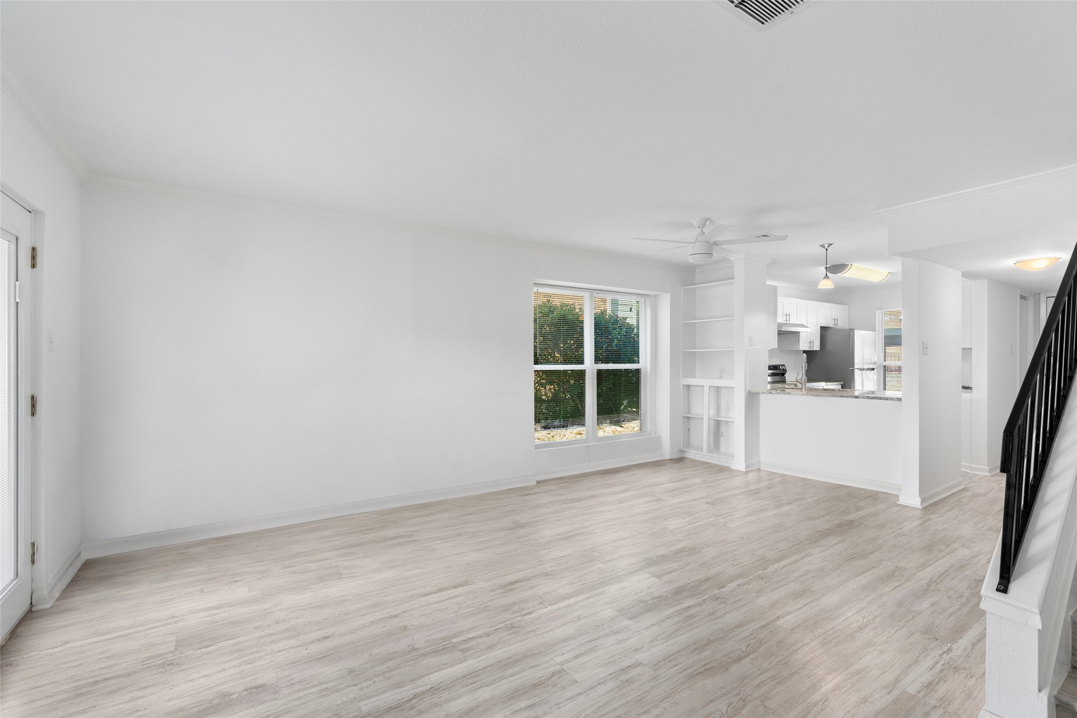 2018 West Rundberg Lane, Unit 16D Austin, TX 78758 - Photo 4 of 18 A well-lit, open-concept living space with light-toned flooring and built-in shelving, seamlessly flowing into a modern kitchen.