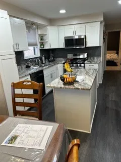 a kitchen with stainless steel appliances kitchen island granite countertop a stove and a cabinets