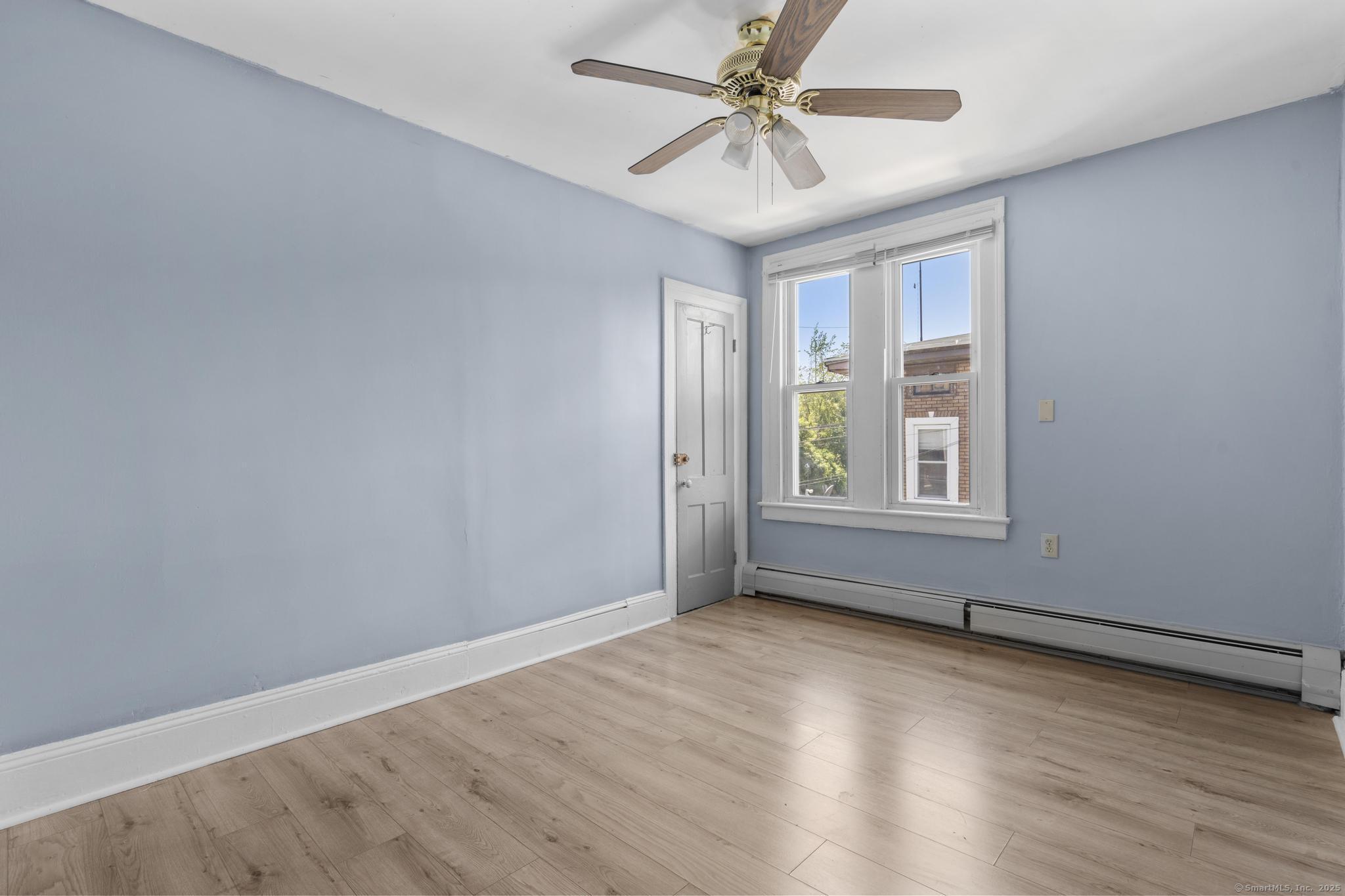 387 Nichols Street, Unit 2 Bridgeport, CT 06608 - Photo 12 of 28 an empty room with wooden floor chandelier fan and windows