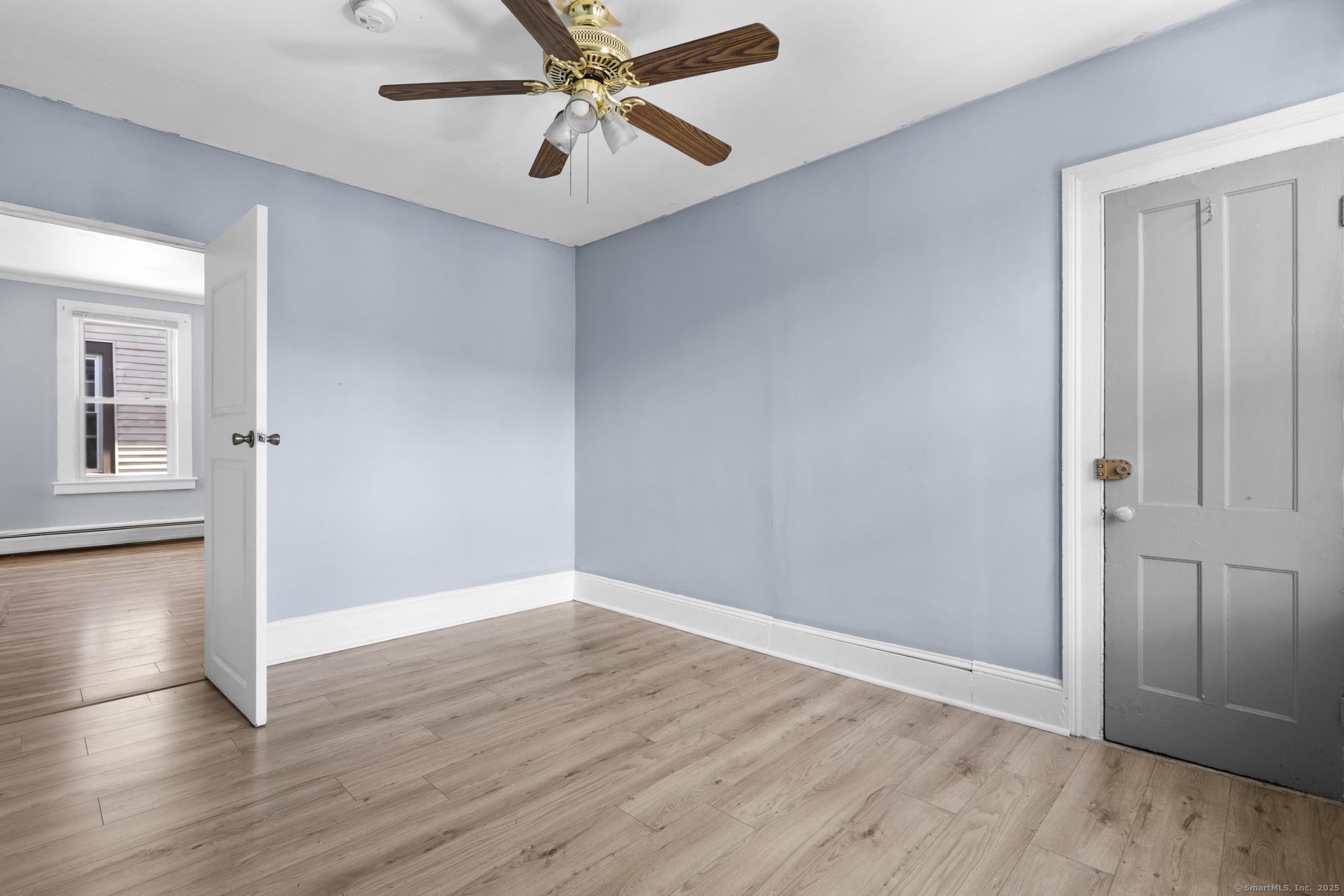 387 Nichols Street, Unit 2 Bridgeport, CT 06608 - Photo 13 of 28 an empty room with wooden floor chandelier fan and windows