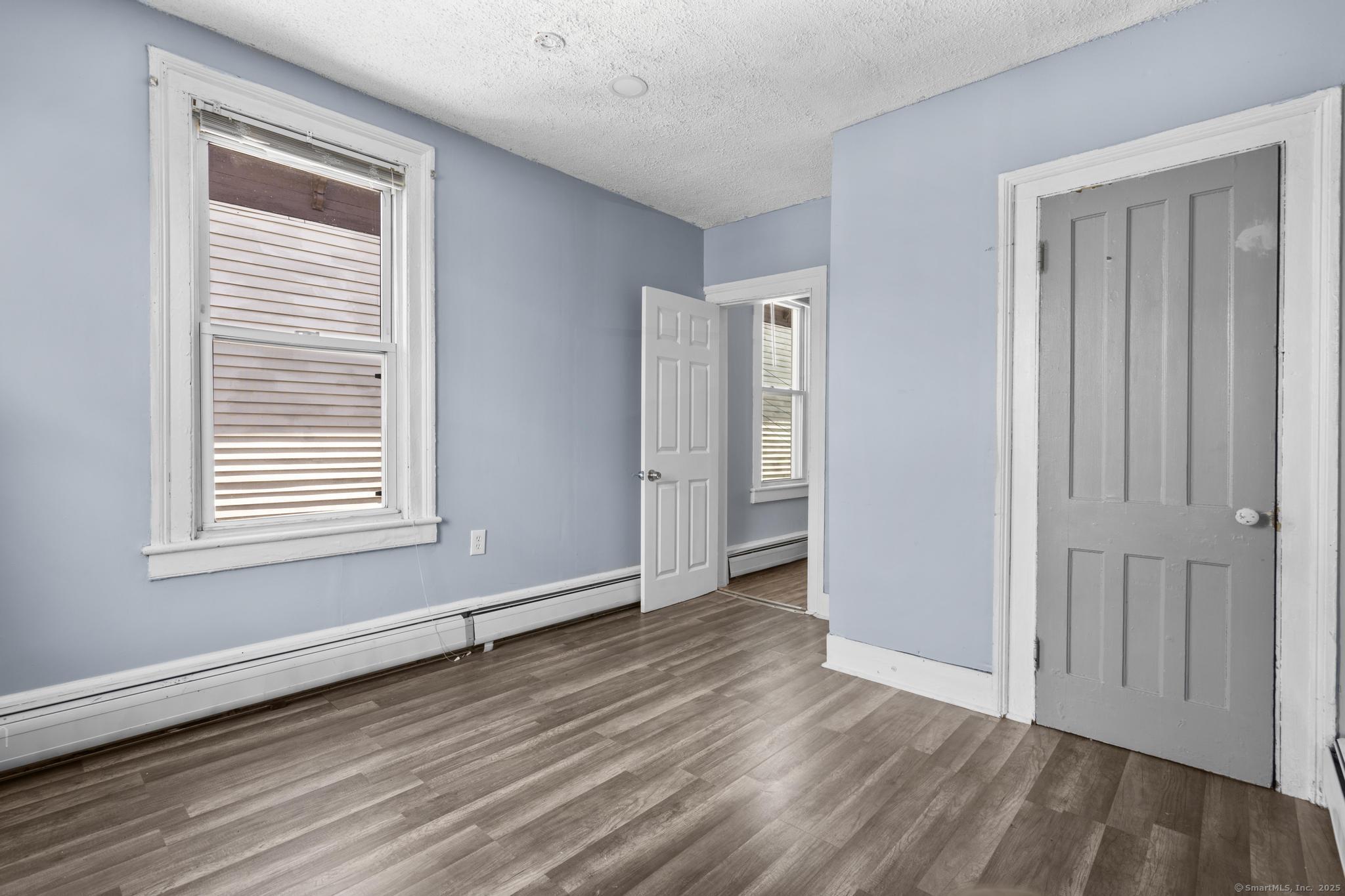 387 Nichols Street, Unit 2 Bridgeport, CT 06608 - Photo 16 of 28 a view of an empty room with wooden floor and a window