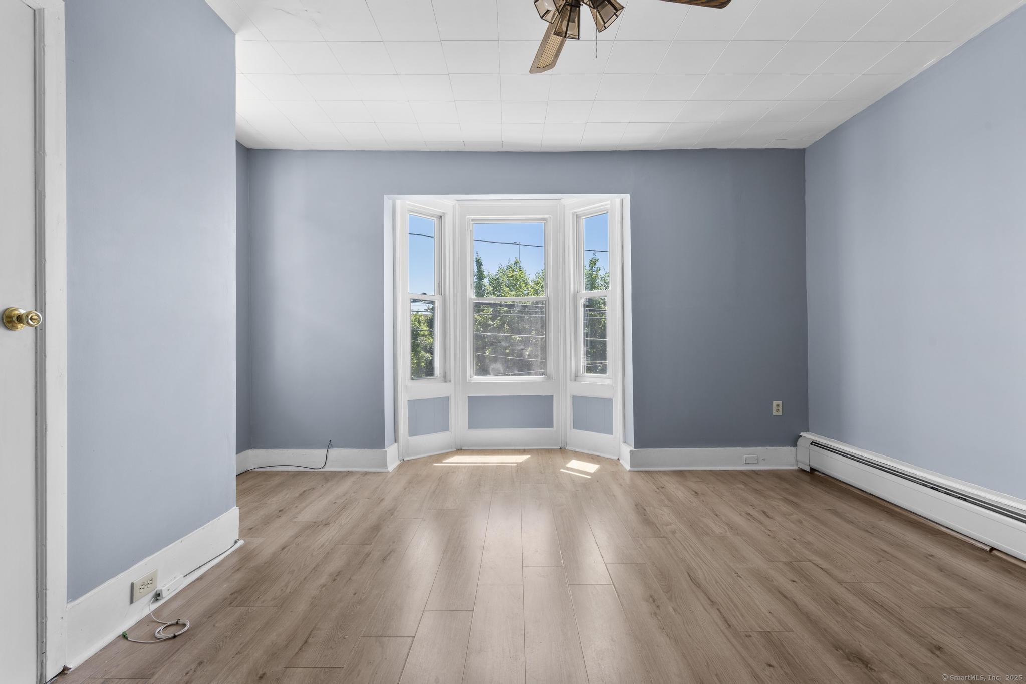 387 Nichols Street, Unit 2 Bridgeport, CT 06608 - Photo 8 of 28 an empty room with wooden floor fan and windows