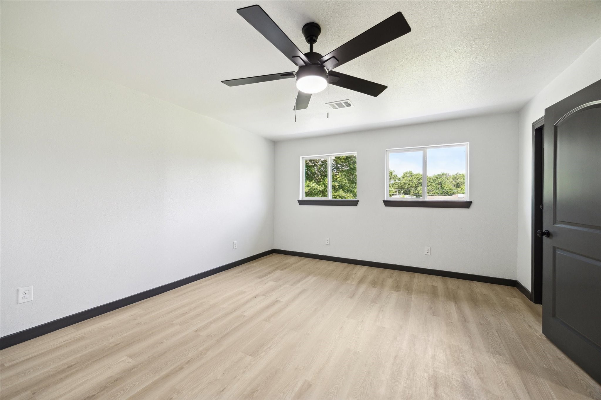 13812 Goodyear Road Dayton, TX 77535 - Photo 8 of 14 an empty room with wooden floor ceiling fan and windows