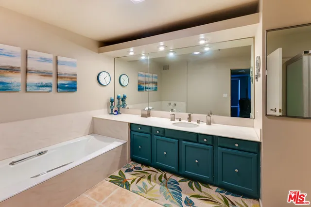 a bathroom with a sink double vanity granite tub and a mirror
