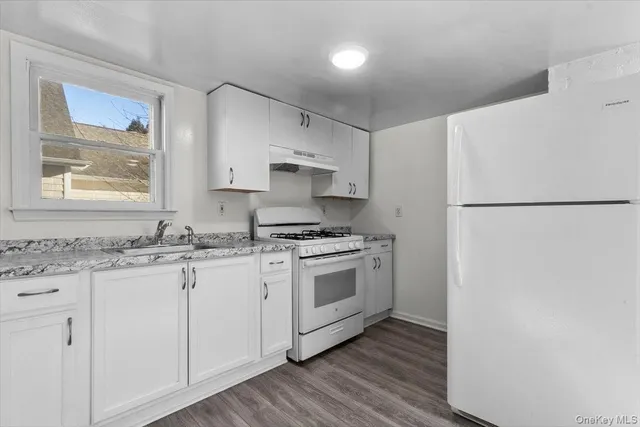 a kitchen with granite countertop white cabinets and white appliances
