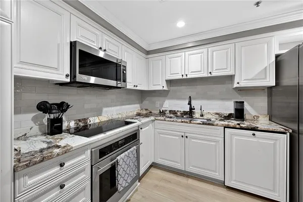 a kitchen with stainless steel appliances granite countertop white cabinets a sink and dishwasher