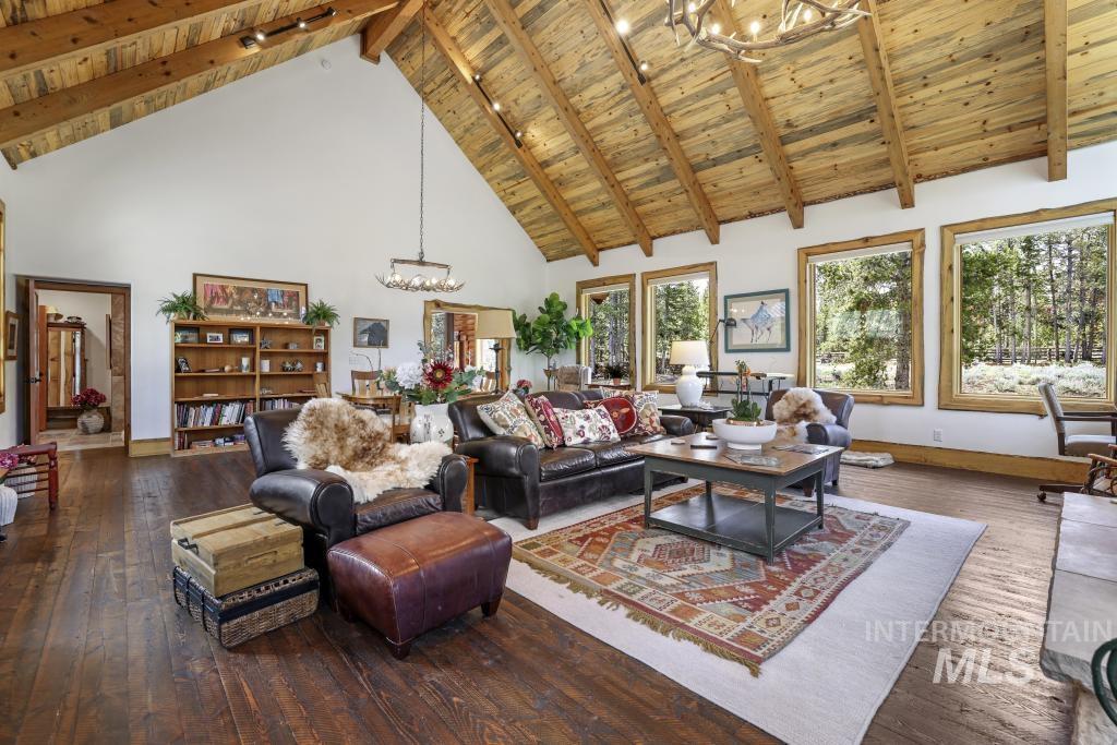 65 Goat Creek Way Stanley, ID 83278 - Photo 7 of 32 Spacious great room featuring a vaulted wood-plank ceiling, exposed wood beams, wood-finish flooring, built-in shelving, and multiple large windows