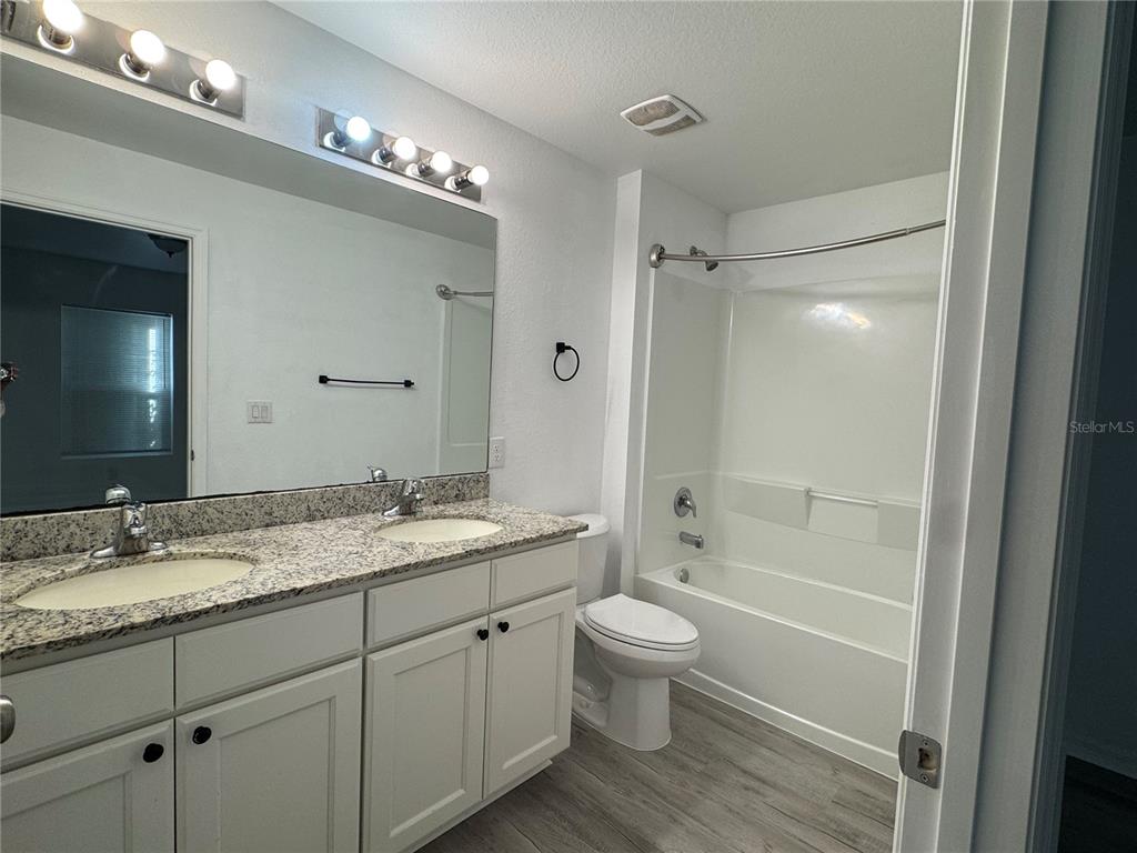 2173 Halblum Street North Port, FL 34288 - Photo 16 of 18 a bathroom with a granite countertop sink toilet a large mirror a bathtub and shower