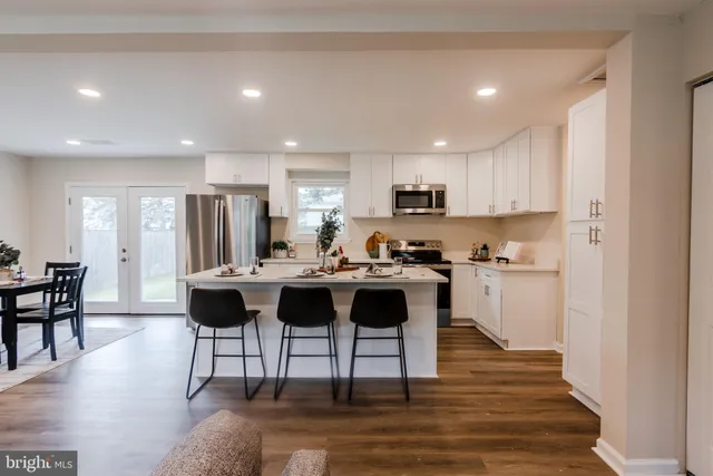 a living room with stainless steel appliances kitchen island granite countertop furniture and a dining table with wooden floor