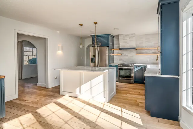 a large kitchen with stainless steel appliances kitchen island granite countertop a refrigerator a stove and a sink with granite countertops