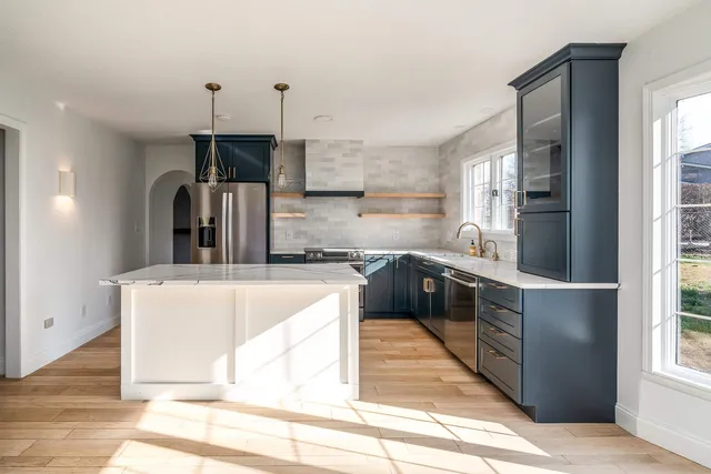 a kitchen with stainless steel appliances granite countertop a sink a stove and a refrigerator