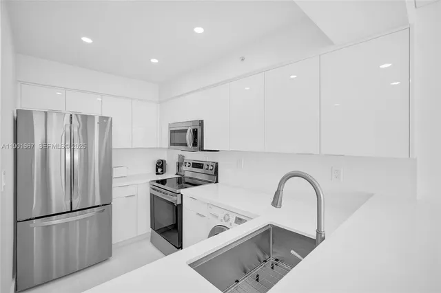 a kitchen with stainless steel appliances a refrigerator sink and white cabinets