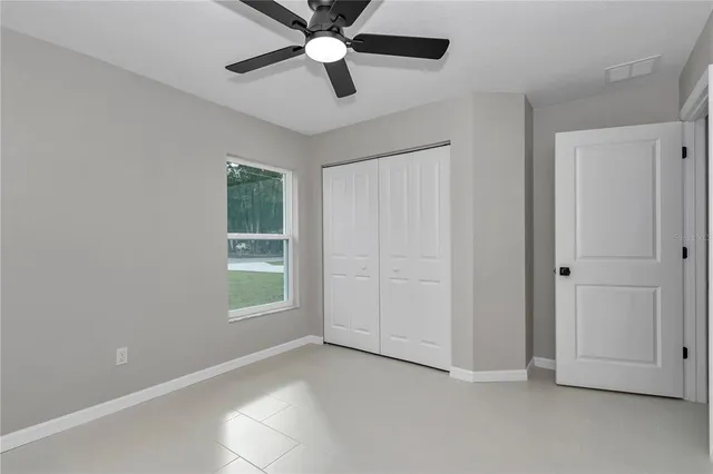 an empty room with a window and a ceiling fan