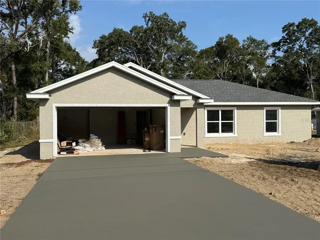 a front view of a house with yard and trees in the background