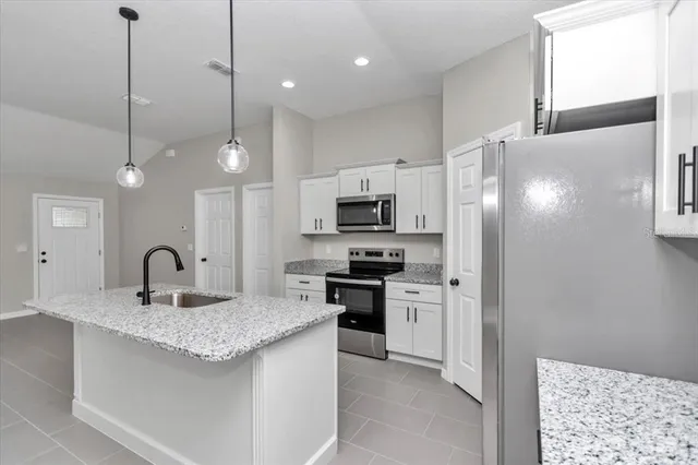 a kitchen with stainless steel appliances granite countertop a sink a stove a refrigerator and island