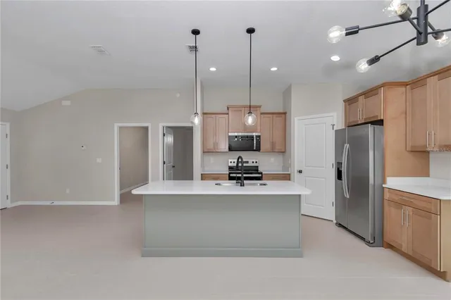 a kitchen with stainless steel appliances a refrigerator a sink a stove a microwave and island