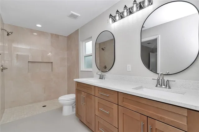 a bathroom with a double vanity sink mirror and toilet