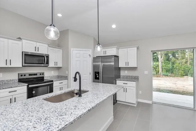 a kitchen with stainless steel appliances granite countertop a sink a stove a refrigerator a center island with wooden floor and cabinets