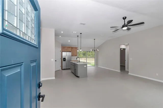 a kitchen with stainless steel appliances a stove a sink a refrigerator a center island with wooden floor