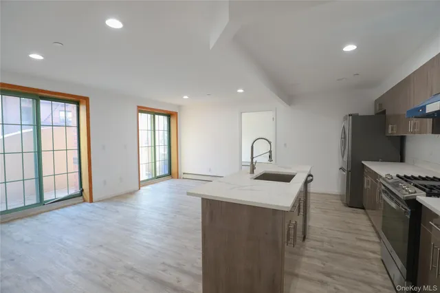 a kitchen with stainless steel appliances granite countertop a sink a stove and a wooden floors