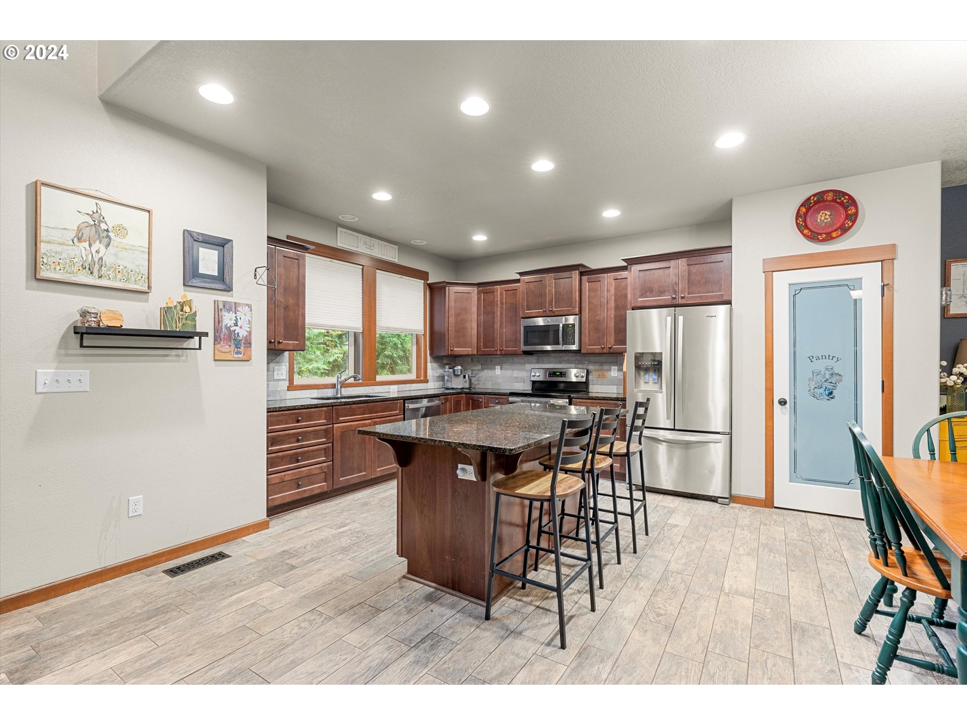 28247 South Moonridge Road Colton, OR 97017 - Photo 5 of 27 a kitchen with stainless steel appliances kitchen island granite countertop a refrigerator a stove a sink a dining table and chairs with wooden floor
