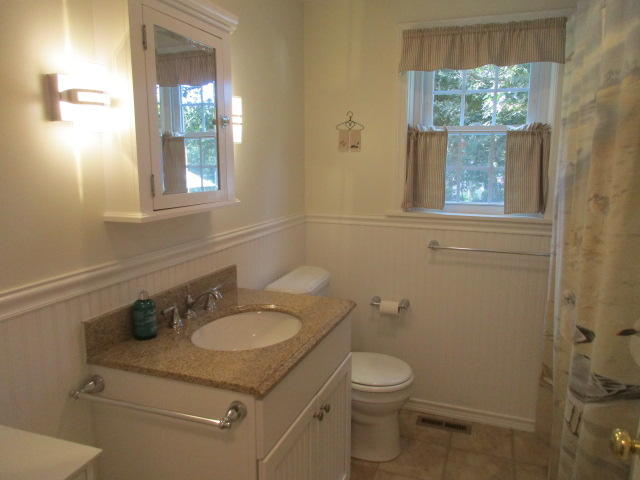 4 Stage Coach Road Harwich, MA 02645 - Photo 15 of 34 a bathroom with a granite countertop toilet a sink a mirror and a window
