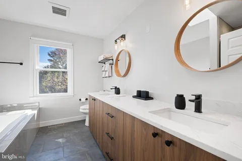 a bathroom with a double vanity sink mirror and bathtub