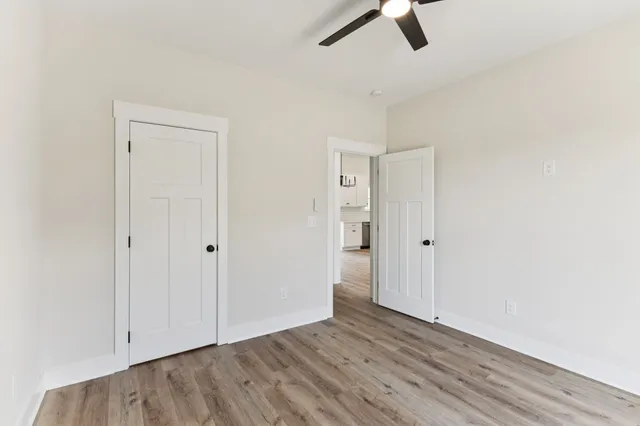 an empty room with a ceiling fan and wooden floor