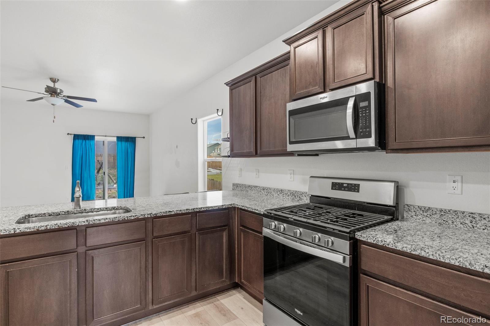 311 Maple Street Bennett, CO 80102 - Photo 11 of 35 a kitchen with stainless steel appliances granite countertop a stove microwave and sink