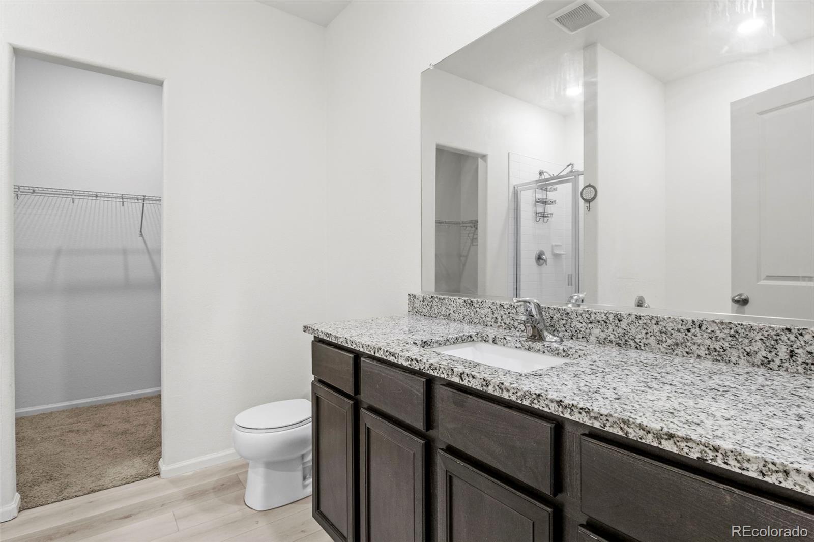 311 Maple Street Bennett, CO 80102 - Photo 22 of 35 a bathroom with a granite countertop sink a toilet and a mirror