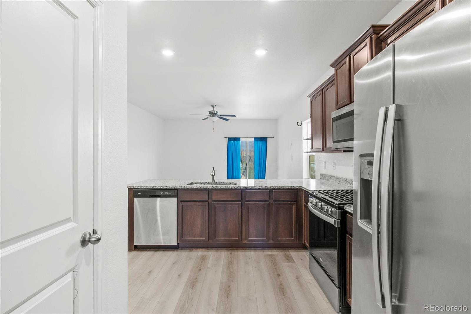 311 Maple Street Bennett, CO 80102 - Photo 10 of 35 a kitchen with stainless steel appliances granite countertop a stove a sink and a refrigerator