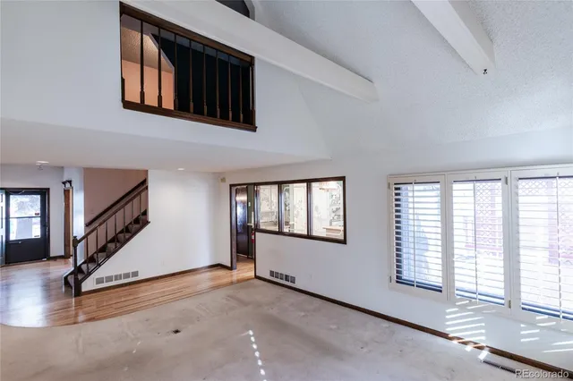 an entryway of a house with wooden floor windows and stairs