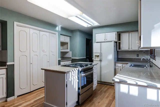 a kitchen with stainless steel appliances granite countertop a stove a refrigerator and a sink with wooden cabinets