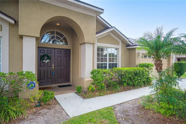 a view of a brick house with a large windows and flower plants