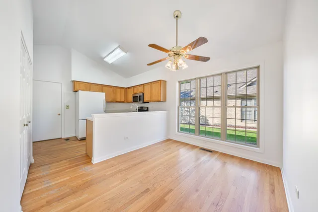 a view of a big room with wooden floor a ceiling fan and windows