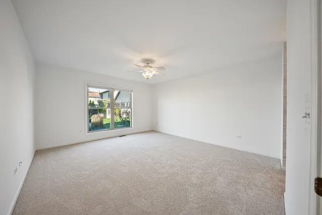 an empty room with a window and a chandelier fan