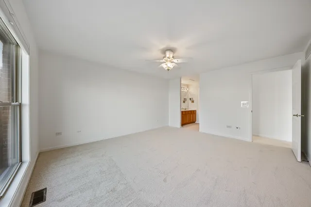 an empty room with chandelier fan and windows