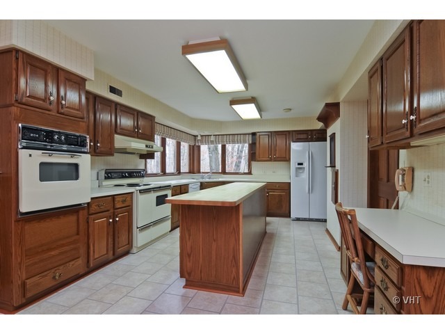 721 Rockefeller Road Lake Forest, IL 60045 - Photo 4 of 10 a kitchen with stainless steel appliances kitchen island granite countertop a refrigerator a sink dishwasher a stove with wooden cabinets